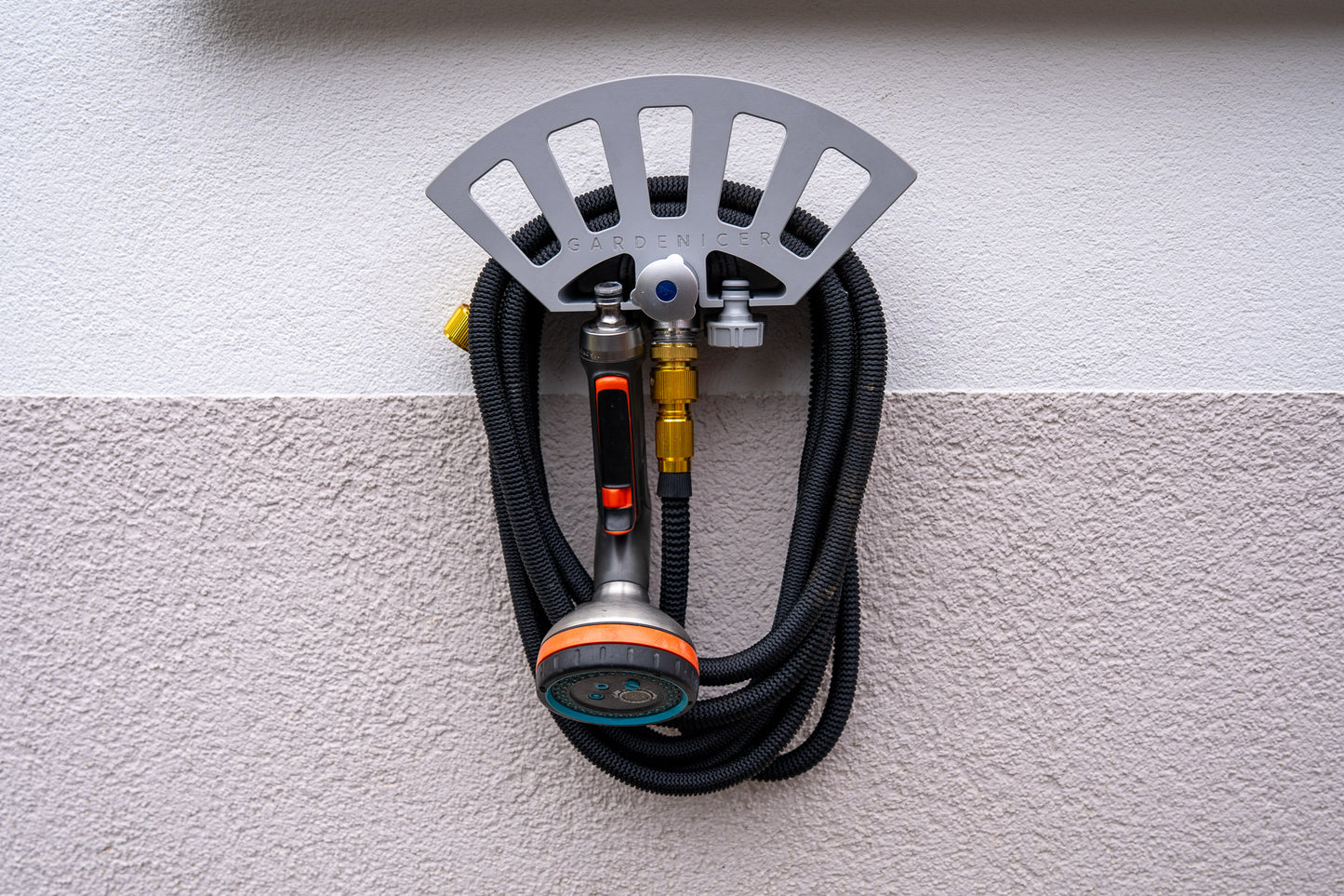 Detailansicht: Gardenicer Classic Schlauchhalter aufgesteckt auf einer kompatiblen Kemper Frosti Außenarmatur, inklusive aufgerolltem Gartenschlauch, Spritzbrause und Adaptern.