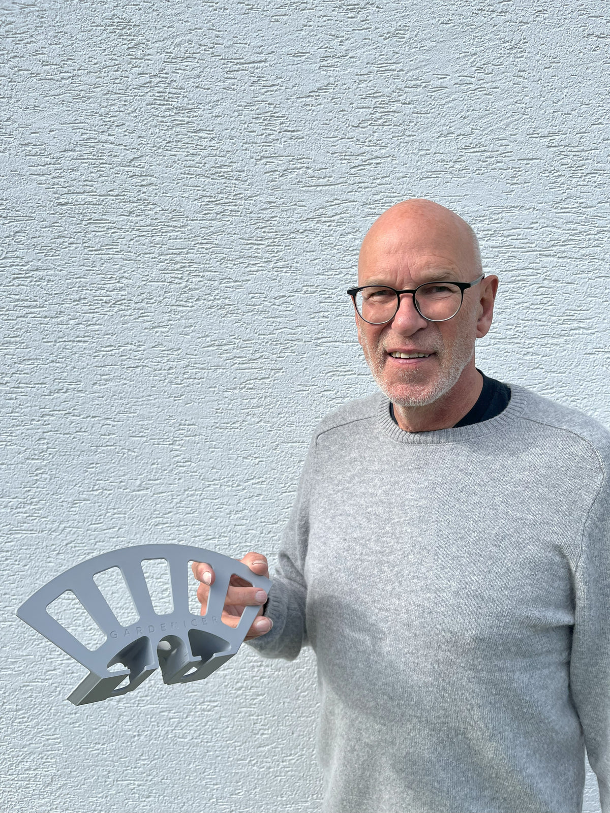 Zufriedener Kunde zeigt den Gardenicer Classic Schlauchhalter: Die smarte Lösung zur Aufbewahrung von Gartenschlauch und Zubehör ohne Bohren an der Hauswand.